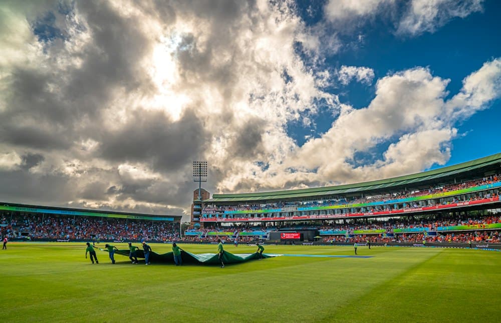 Cricket ground with groundstaff covering the pitch